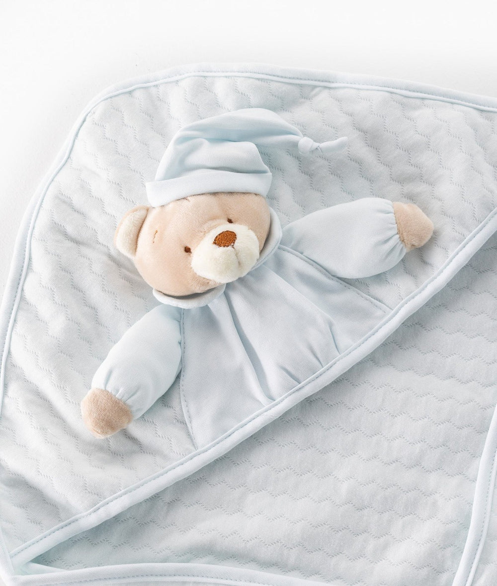 Close-up of light blue swaddle with beige bear applique wearing nightcap and diamond stitching