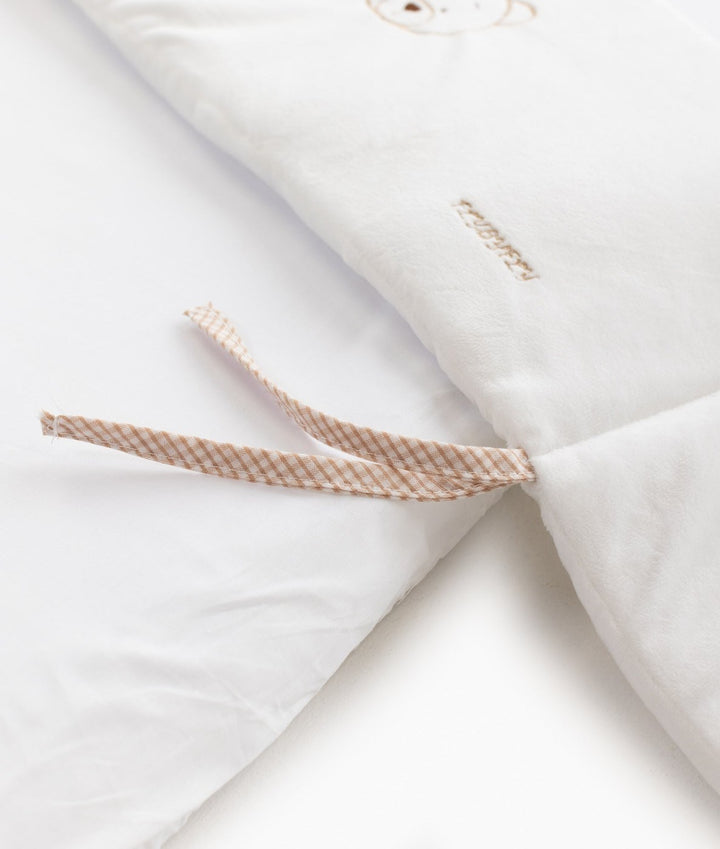 Close-up of white plush blanket tie tabs and subtle embroidered text branding