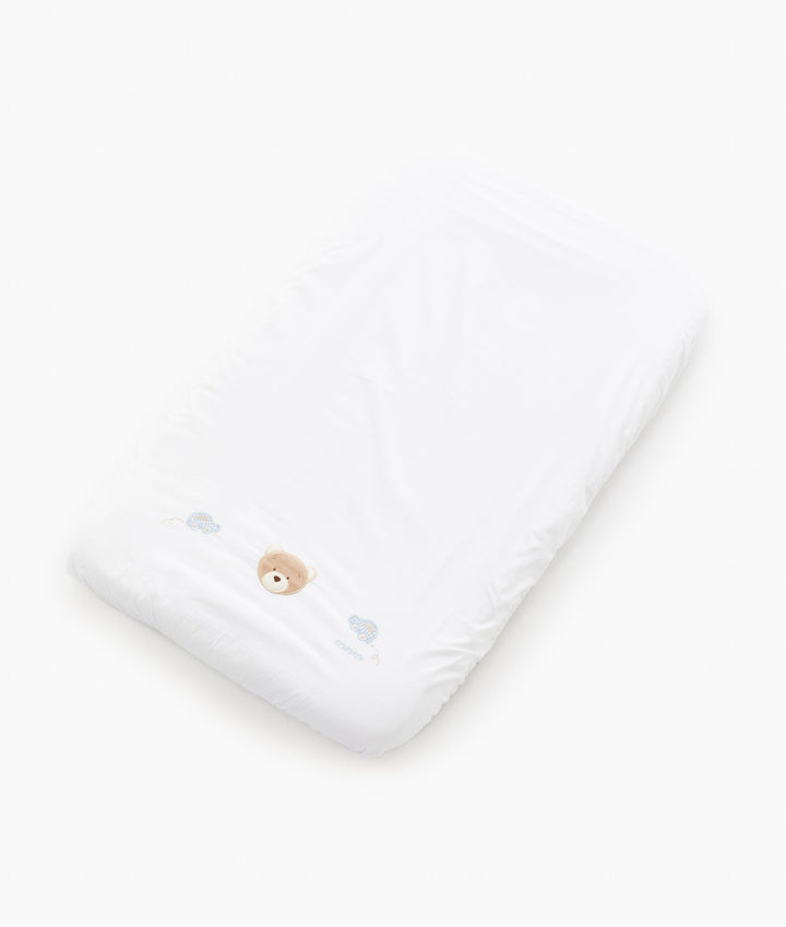 White fitted bassinet sheet with embroidered bear head and blue car motifs