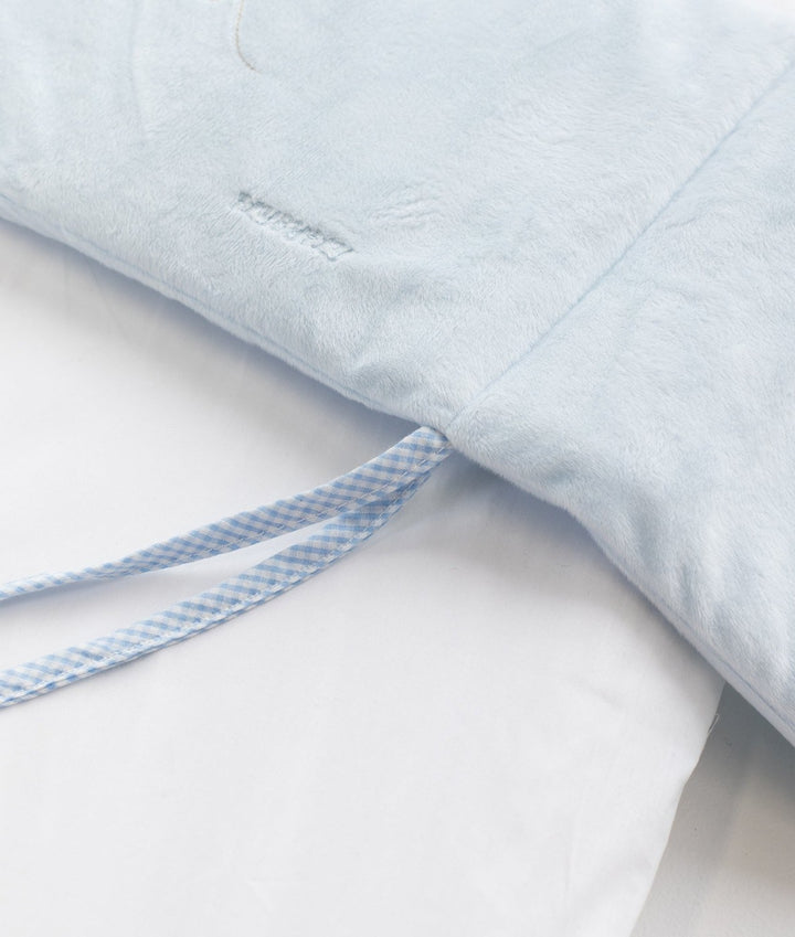 Soft light blue plush bassinet bumper with gingham tie strap against white sheet