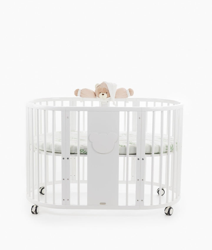 White baby cot with teddy bear design styled in a neutral nursery room