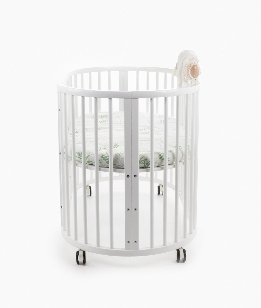 White baby cot with teddy bear design styled in a neutral nursery room