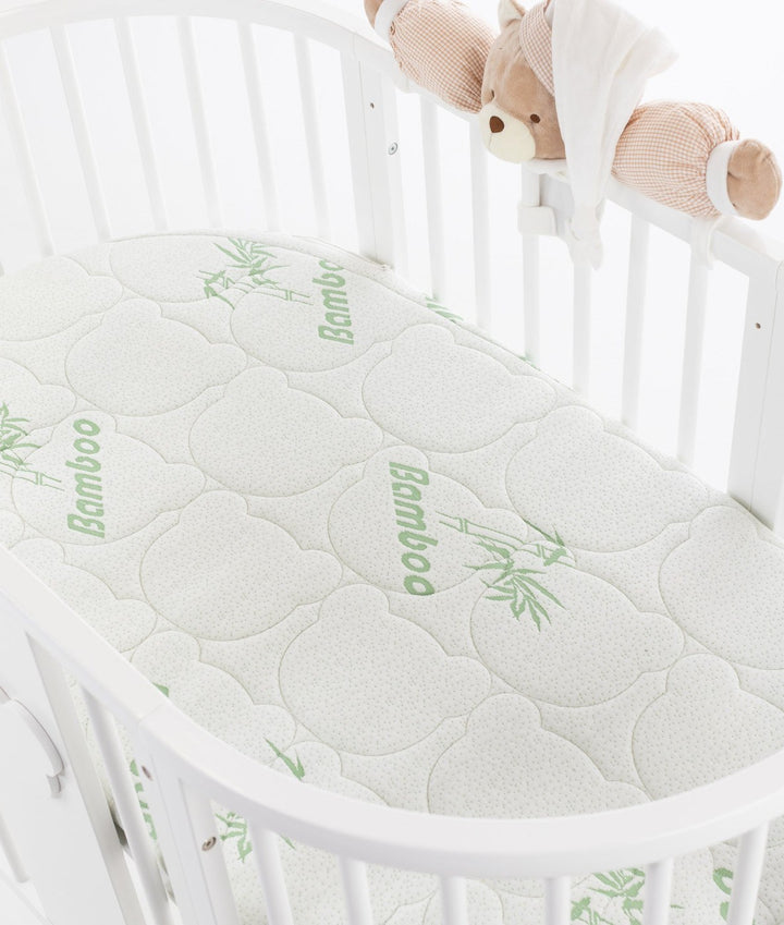 White baby cot with teddy bear design styled in a neutral nursery room