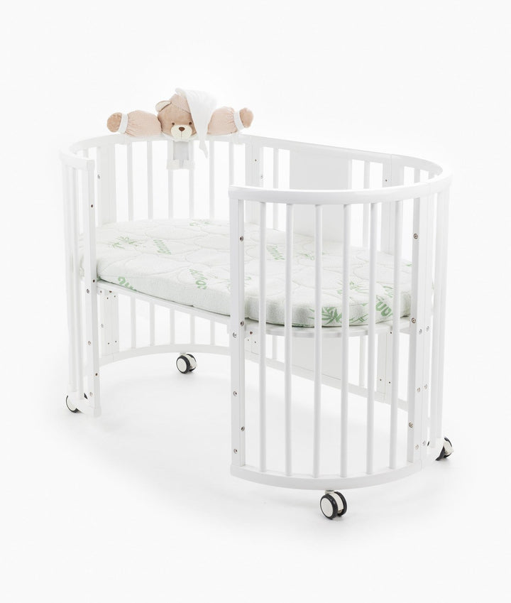 White baby cot with teddy bear design styled in a neutral nursery room