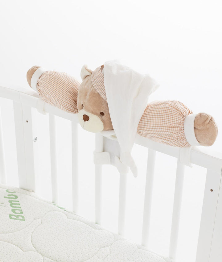 White baby cot with teddy bear design styled in a neutral nursery room