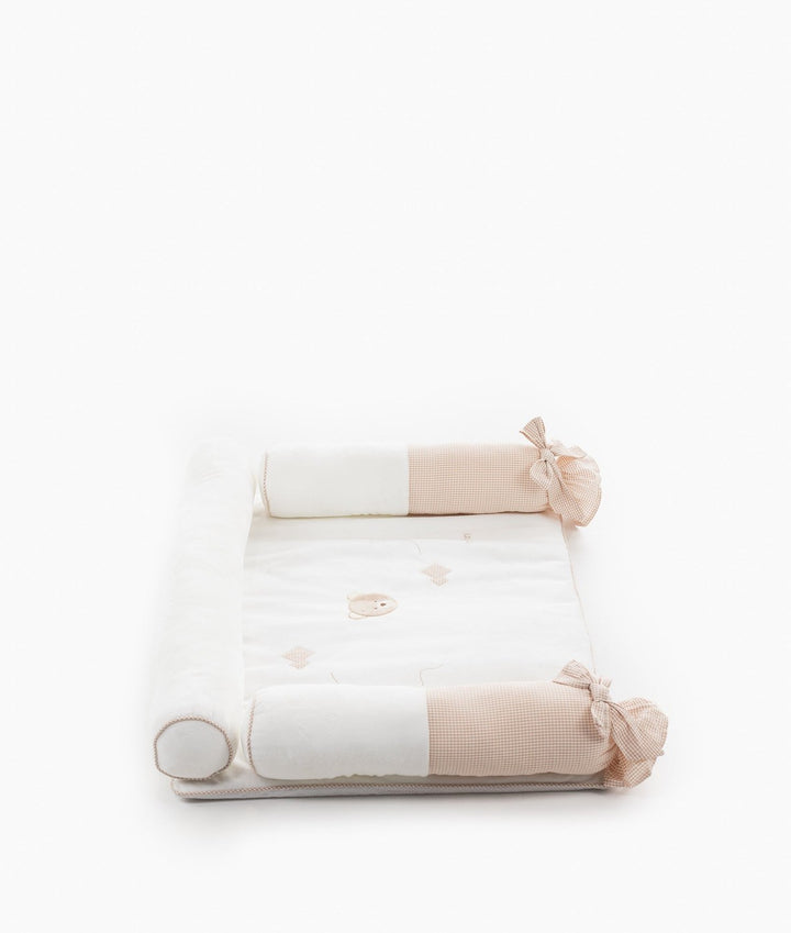 Top down flat lay of beige and white cotton change mat set with support bolsters