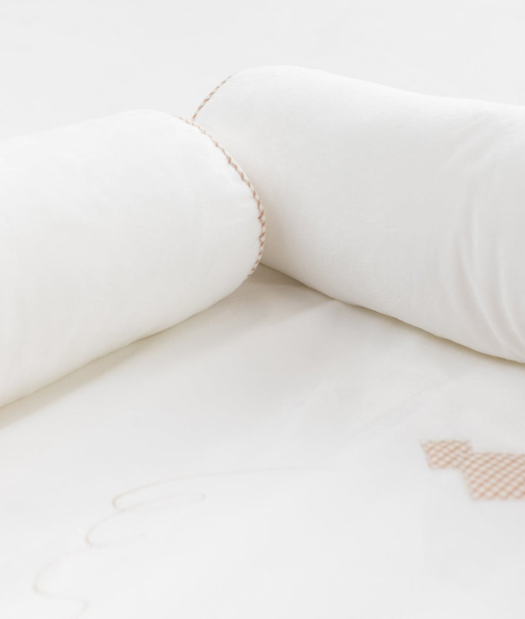 Close-up of soft white plush bolster padding with beige braided trim stitching