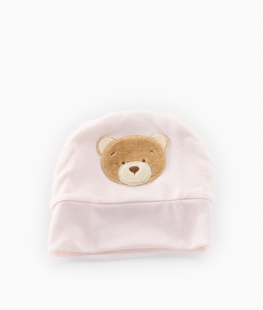 Front view of soft pink knit baby hat with brown teddy bear patch on folded brim