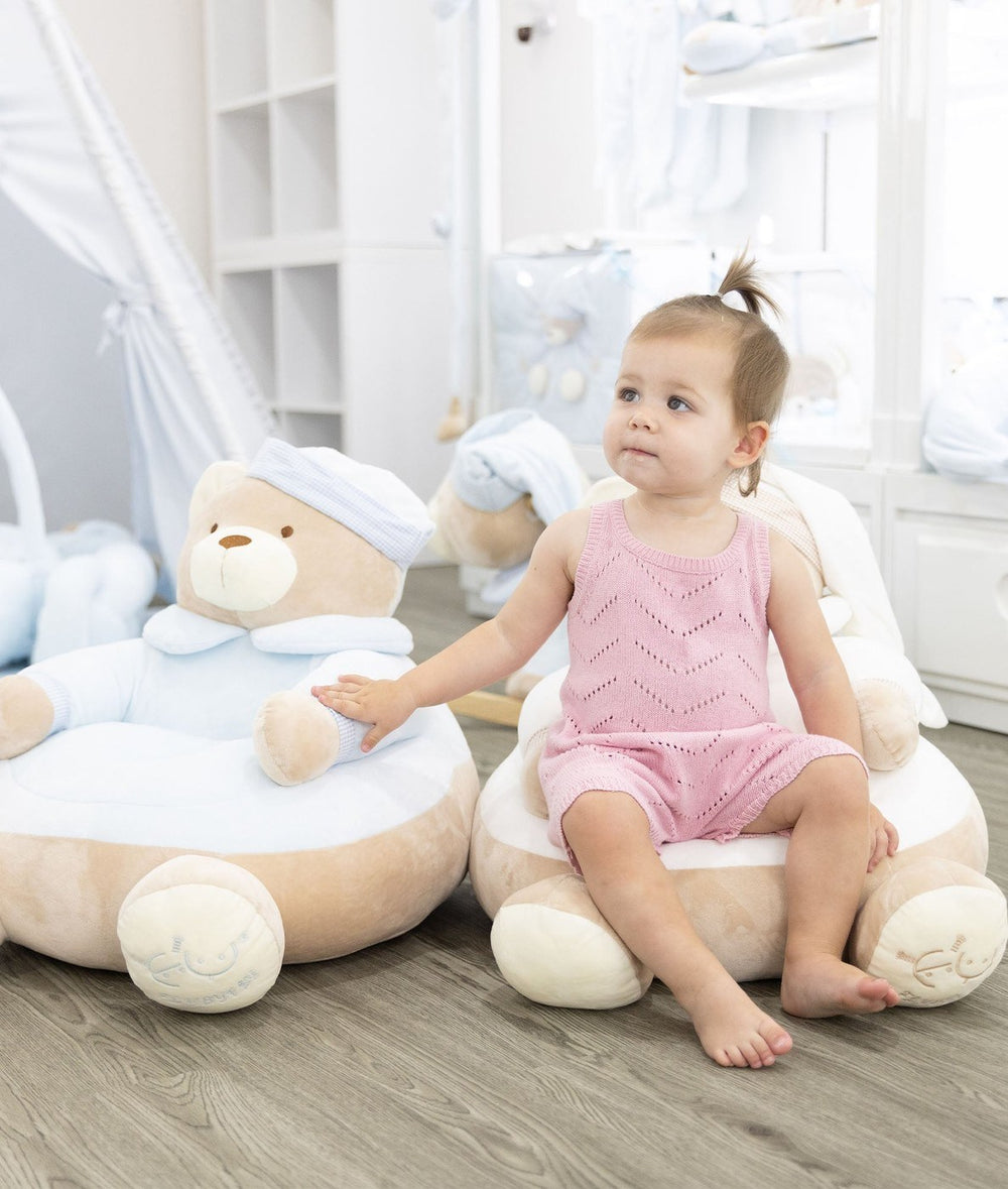 Lifestyle shot of toddler sitting on white bear chair next to blue version in nursery
