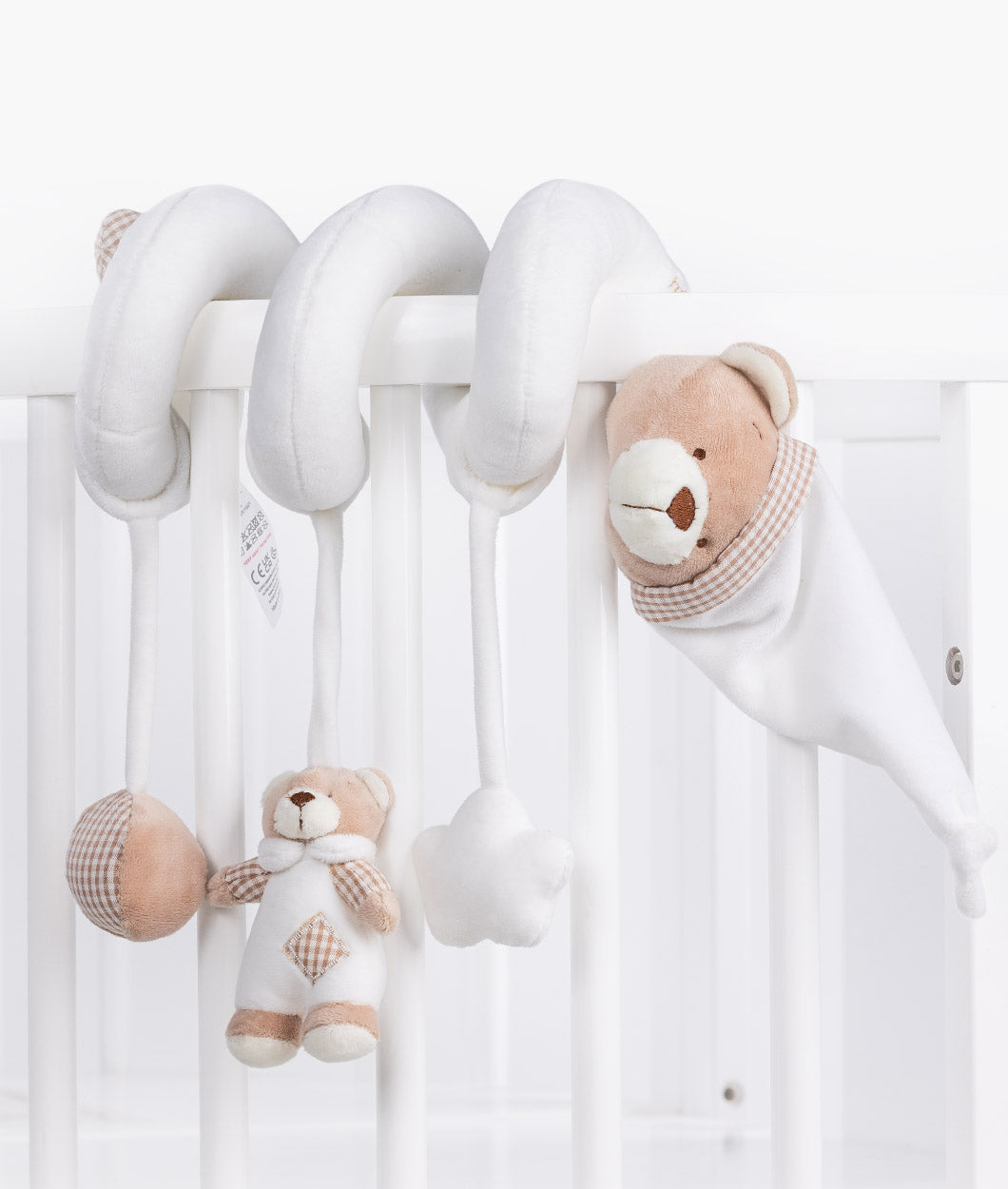 Bear spiral activity toy draped over cot bars showing hanging sensory charms