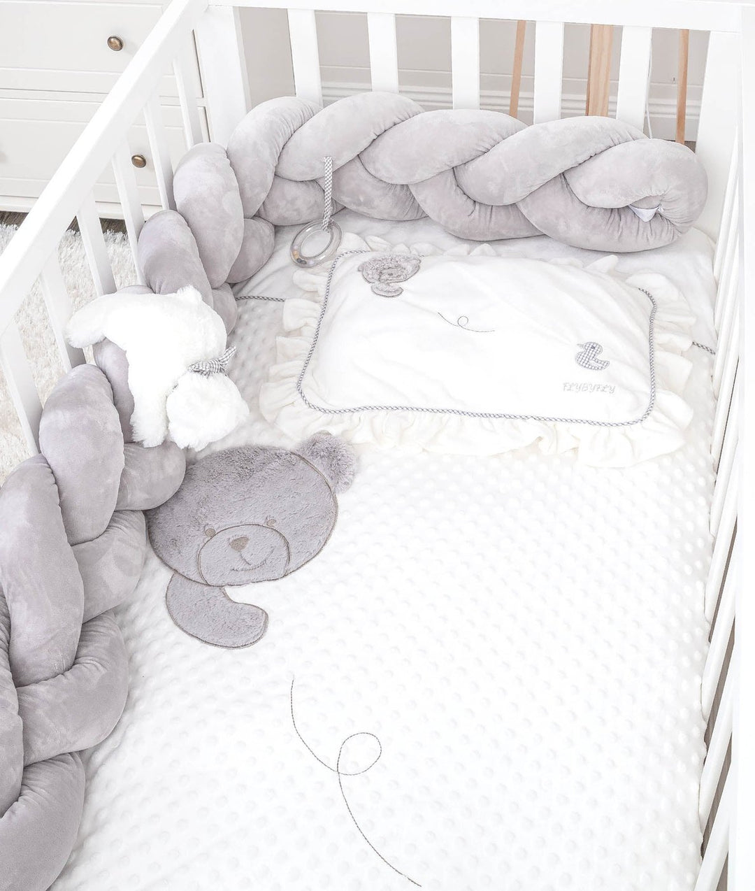 toddler crib setup with grey bumper, ruffled pillow, and bear applique sheet