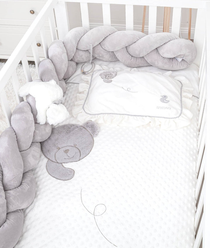 toddler crib setup with grey bumper, ruffled pillow, and bear applique sheet