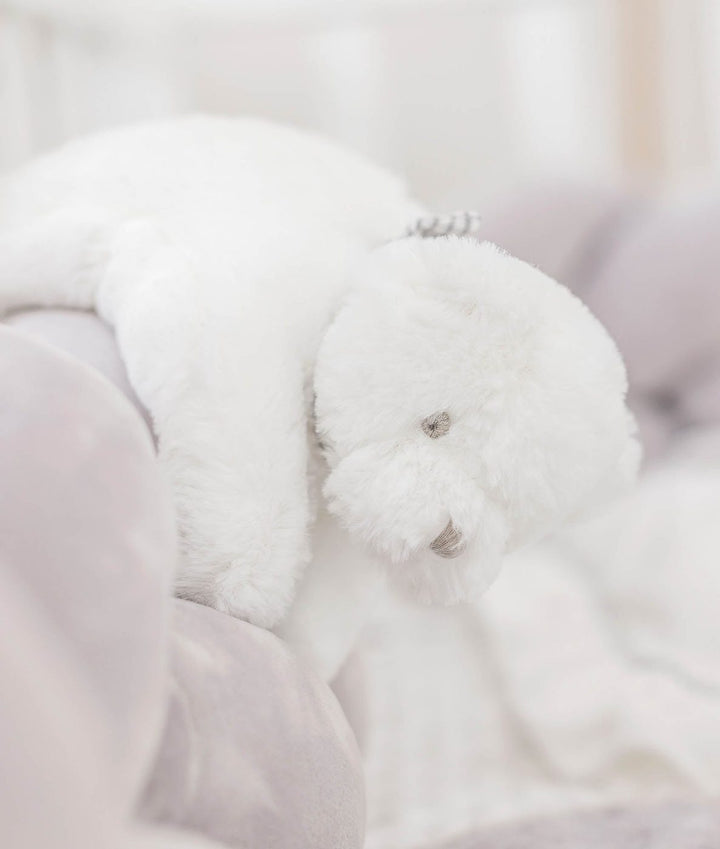 white plush teddy bear with silver sequin ear detail on grey velvet bedding