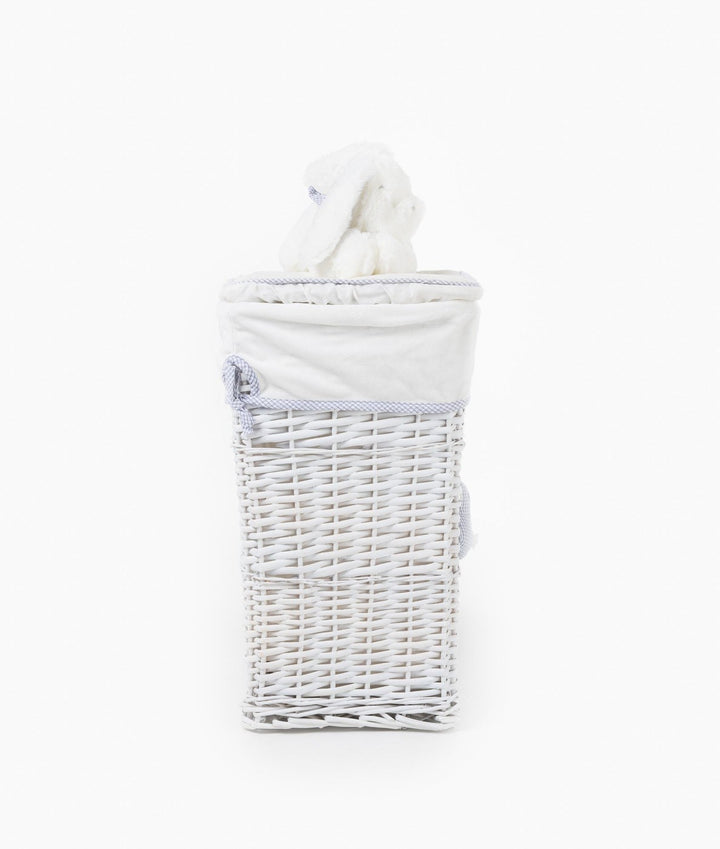 Back view of white wicker laundry basket with cream liner, blue gingham trim, and bunny toy peeking out
