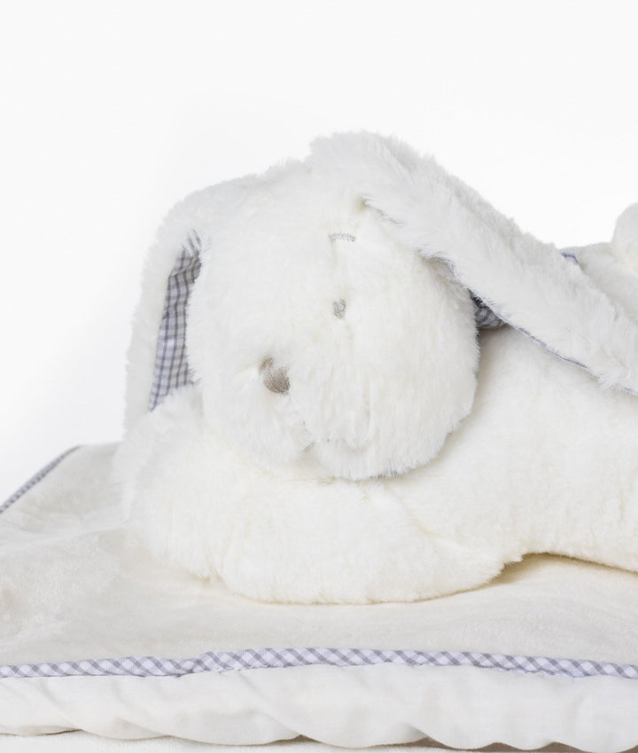 Side view of white plush bunny on cream fabric lid with grey gingham piping trim on wicker basket