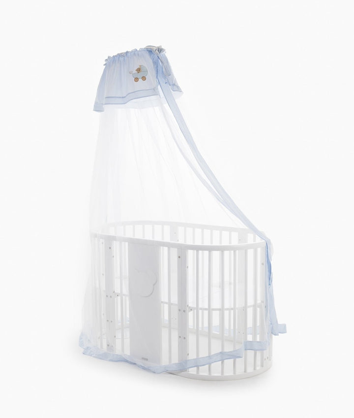 Sheer white netting cot canopy draped over white oval crib with light blue gingham hem trim and side tie straps