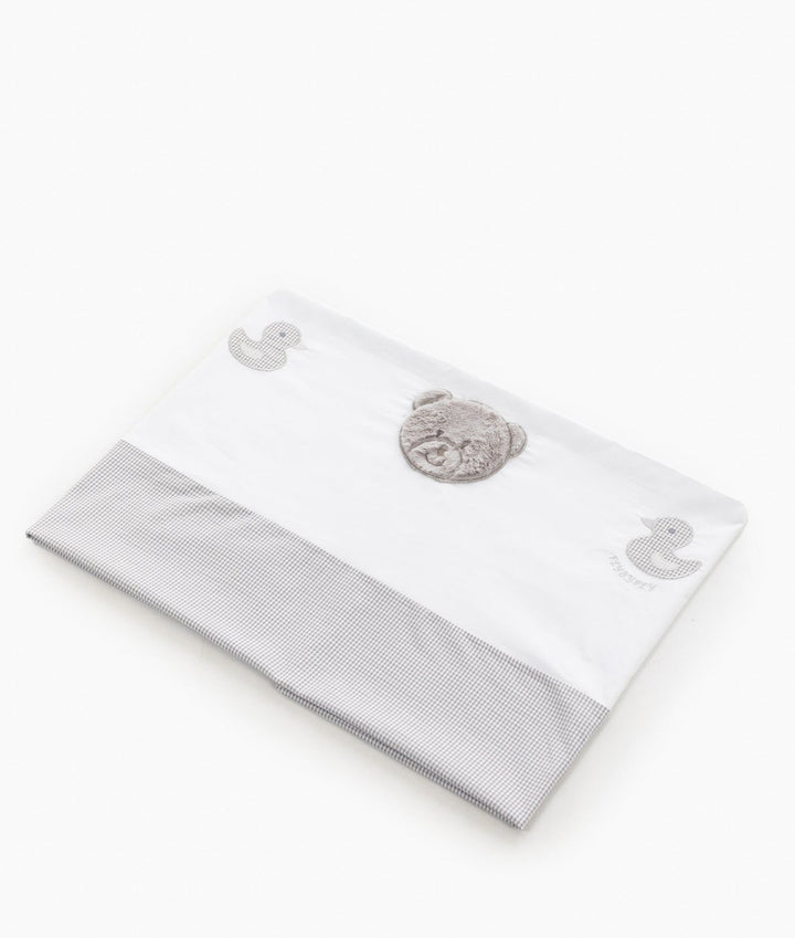 Folded white cotton flat sheet showing grey gingham hem and plush bear patch