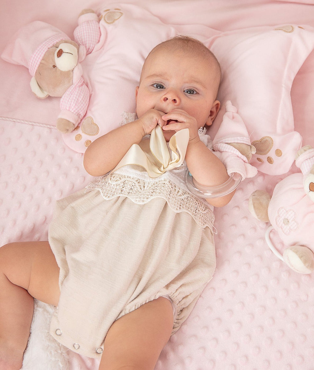 Baby using pink bear-shaped head support pillow on dotted blanket for gentle positioning