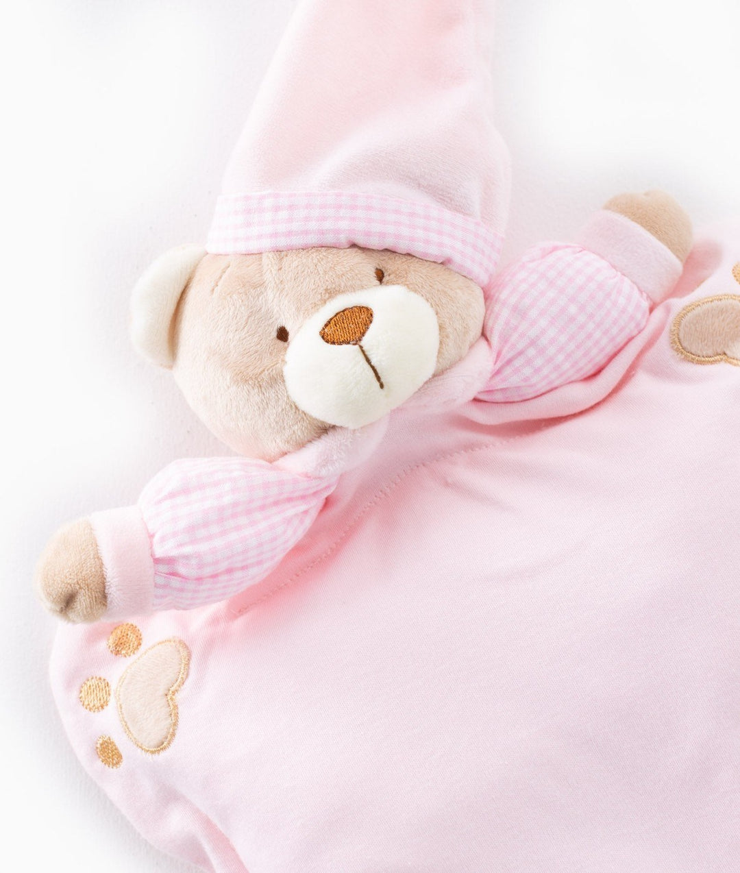 Detail of pink infant pillow teddy bear face with white muzzle, brown nose, and gingham hat band