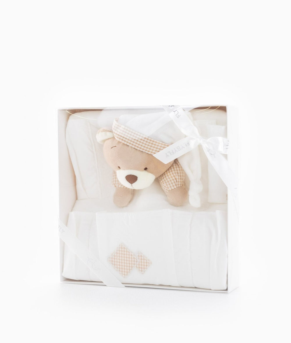 White gift box containing folded cream nursery organiser with beige gingham accents and teddy bear wearing checkered hat