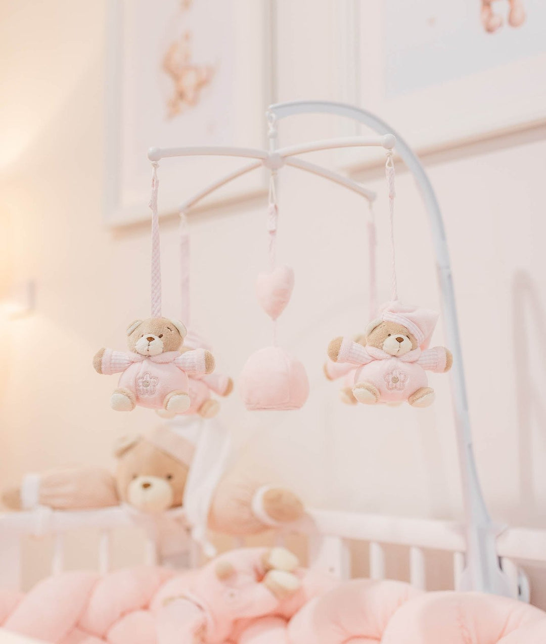 White arched baby mobile stand with pink checkered bear plushies and heart ornaments