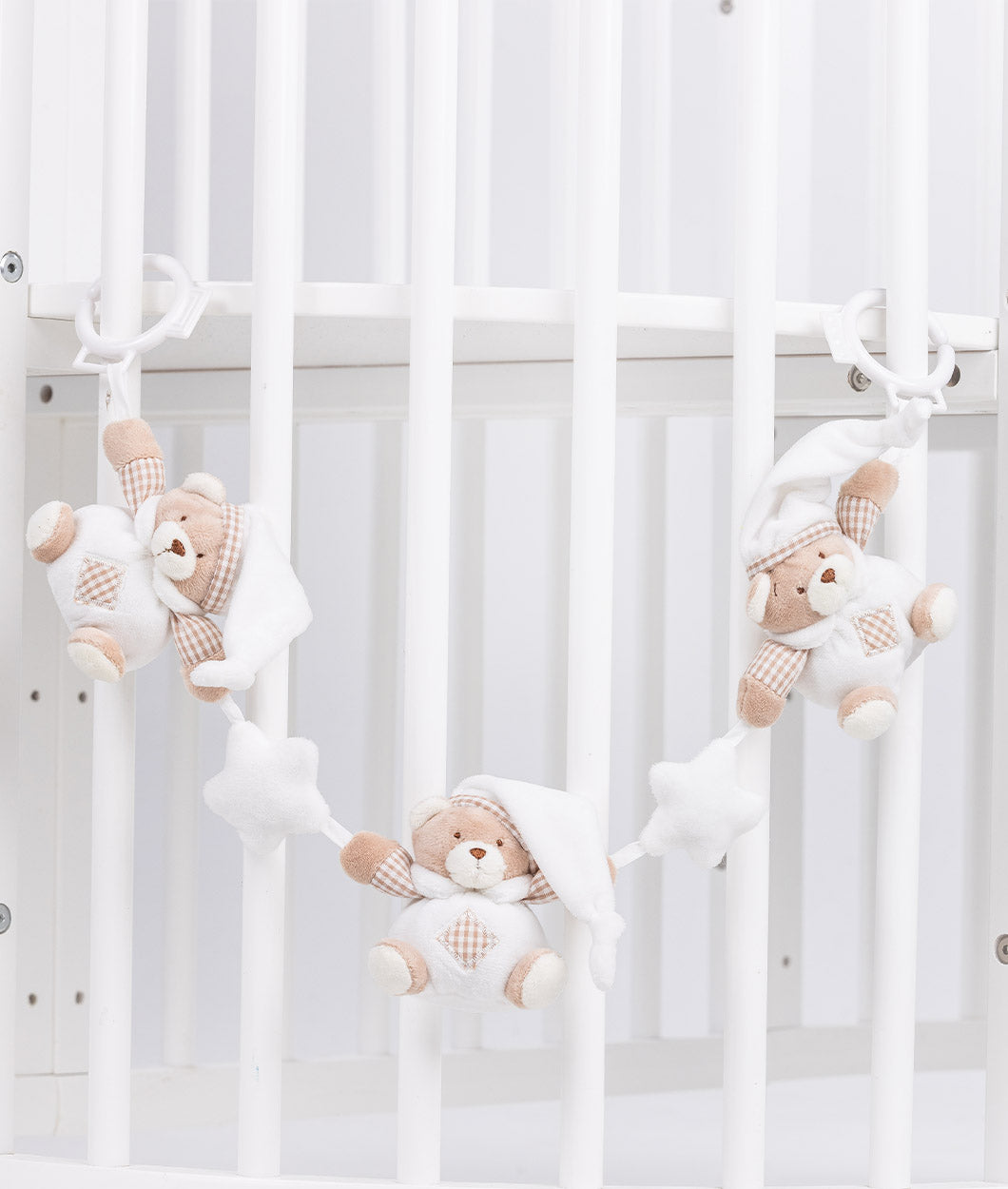 Baby activity toy draped over crib bars featuring sleeping bear dolls with star accents