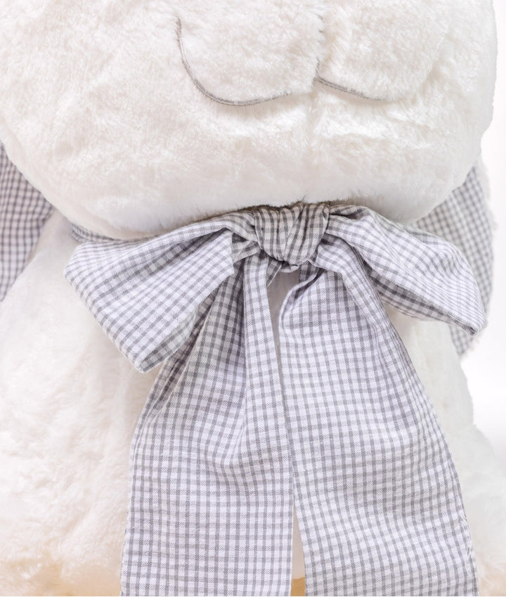 Macro detail of grey and white gingham bow tie on white plush rocking animal highlighting woven texture