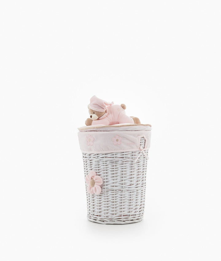 Full shot of white wicker storage basket with pink flower and teddy bear