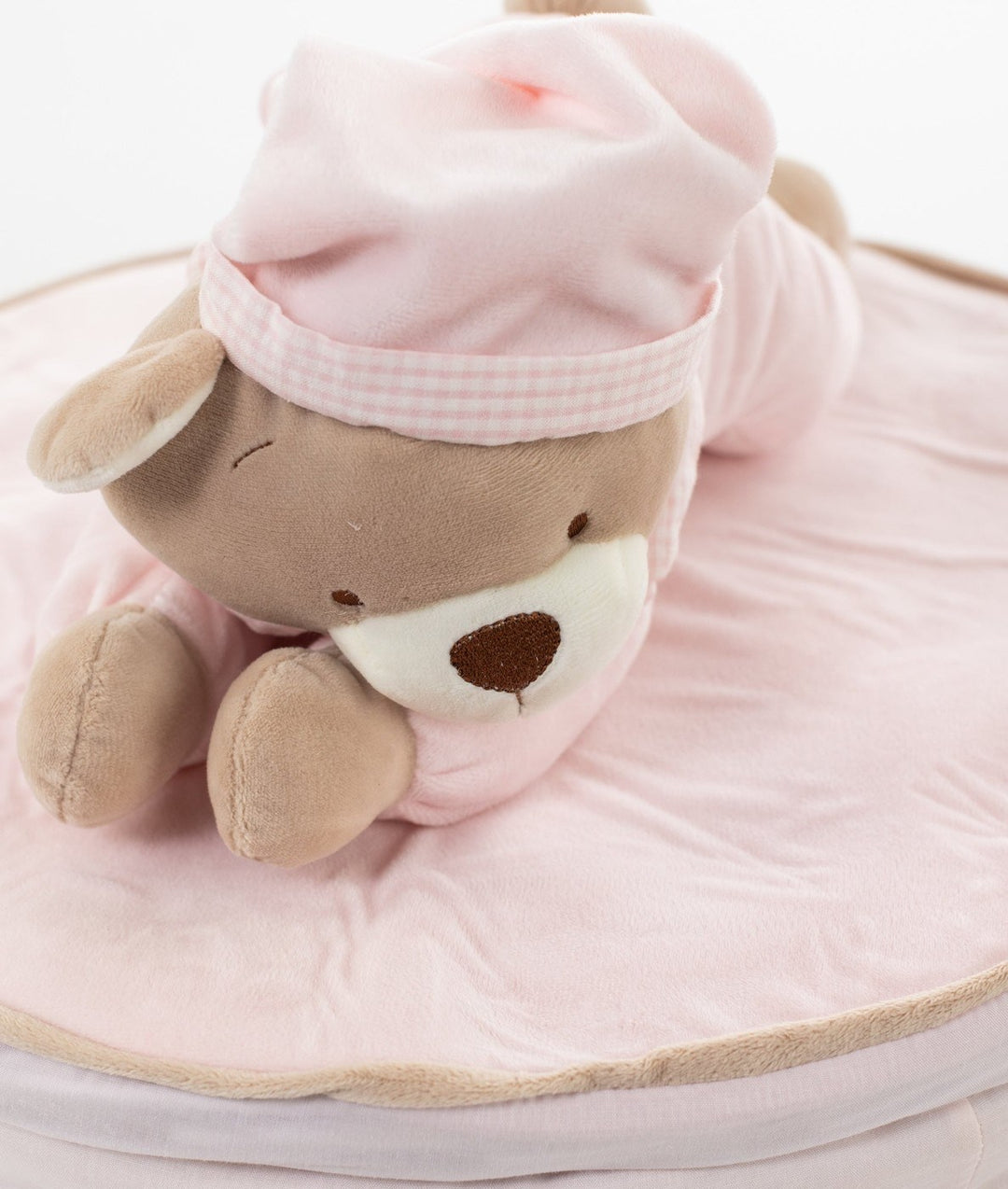 Detail of brown teddy bear on pink quilted wicker basket lid cover