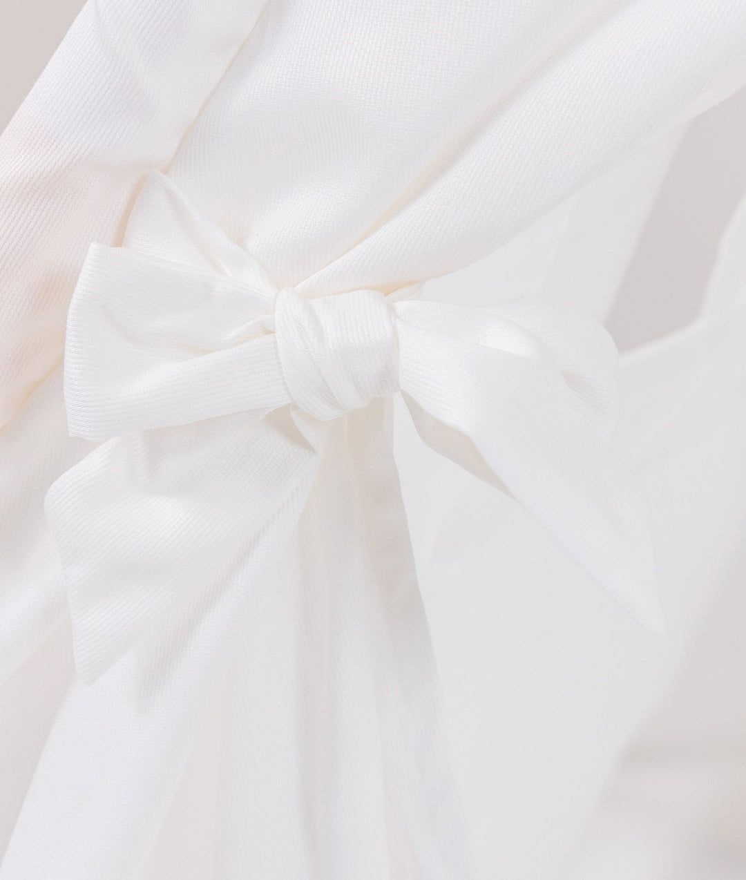 Detail of white cotton tie-back knot at the entrance of a grey and white teepee