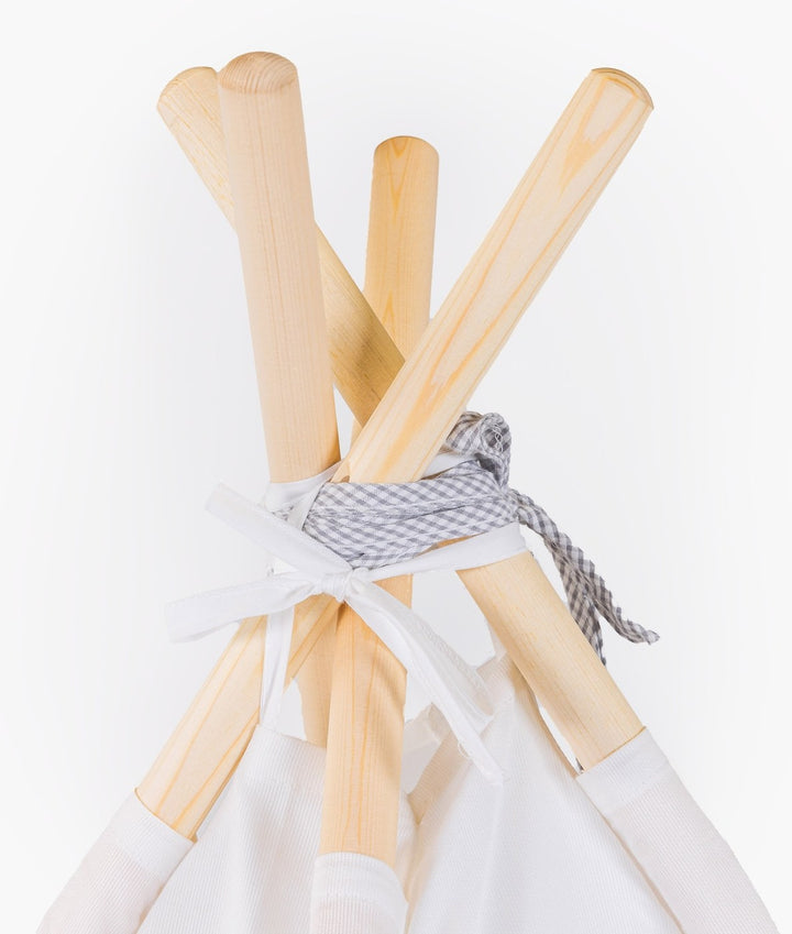 Top-down view of light wood poles tied with grey gingham ribbon at teepee apex