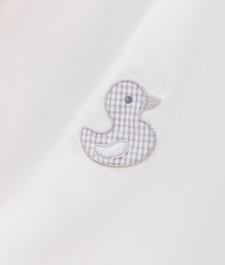 Macro shot of grey gingham rubber duck patch with silver thread on white canvas tent
