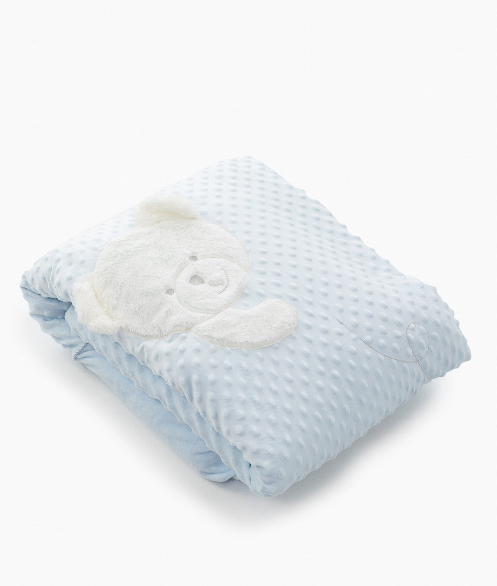 Folded light blue bubble quilt cover showing soft raised dot texture and teddy patch