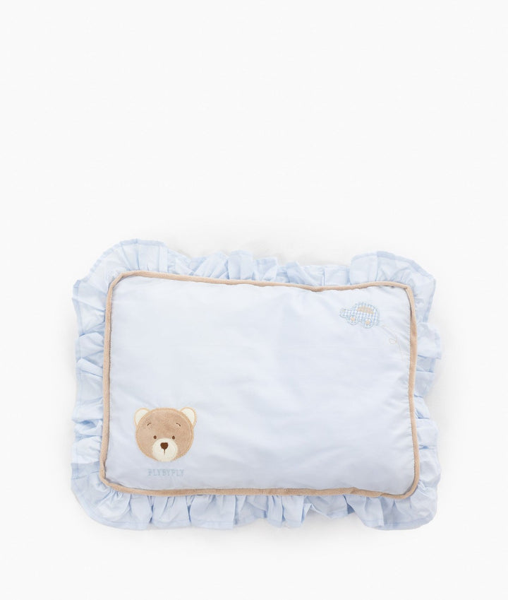 Flat lay of rectangular blue toddler ruffle pillow featuring brown teddy bear applique, brand name, checkered car embroidery, voluminous ruffles, and tan trim