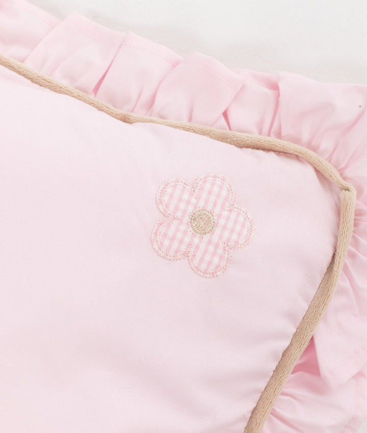 Close up of pink cotton pillow corner with gingham flower patch and beige piping