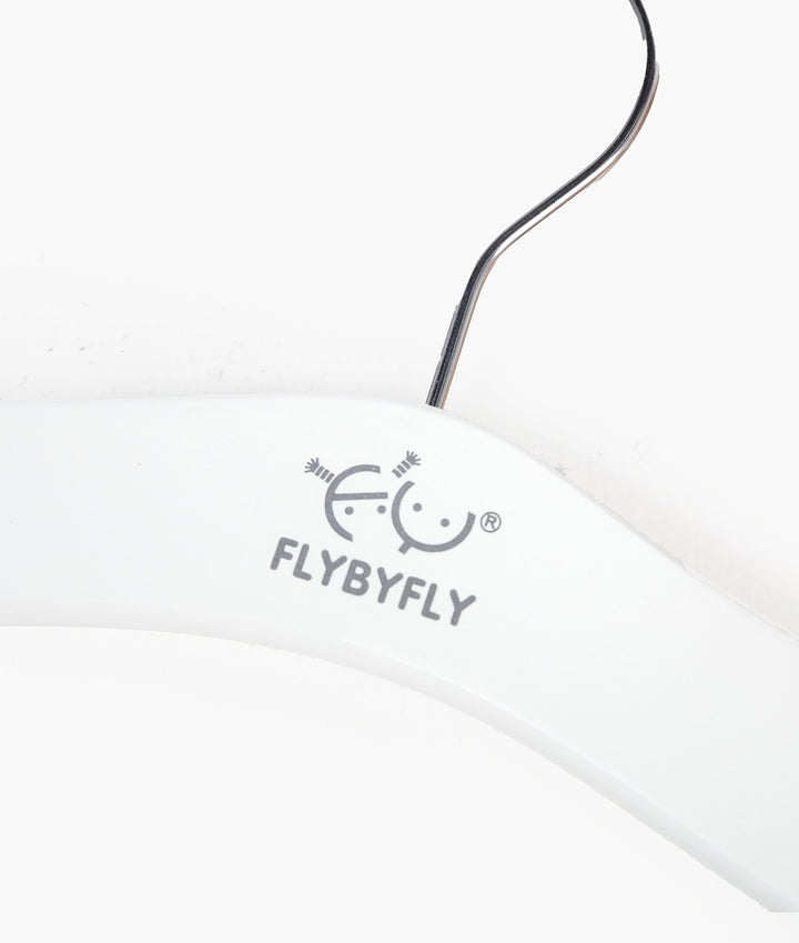 Close-up of white wooden baby hanger surface with grey FLYBYFLY logo print